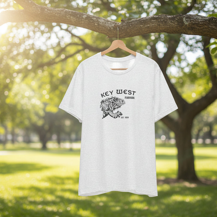 White t-shirt with 'Key West' print hanging on a tree branch in a park.