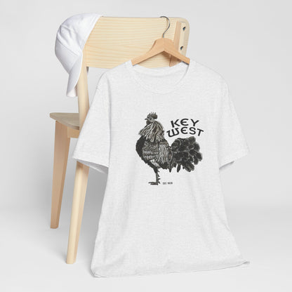 White t-shirt with rooster graphic and 'Key West' text on a wooden chair.