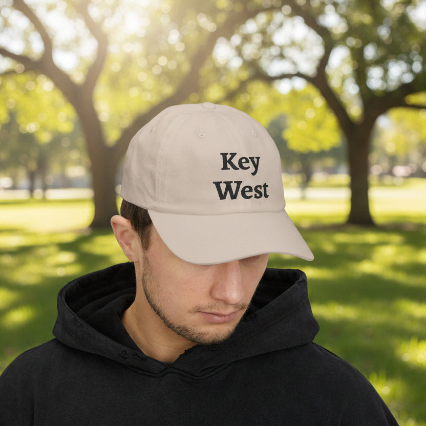 Man wearing a beige cap with 'Key West' text in a park setting