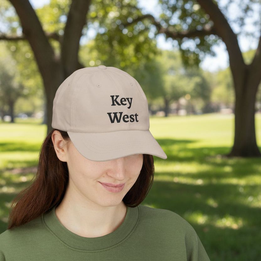 Person wearing a beige cap with 'Key West' text in a park setting