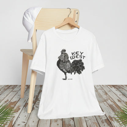 White t-shirt with rooster graphic and 'Key West' text on a wooden chair.