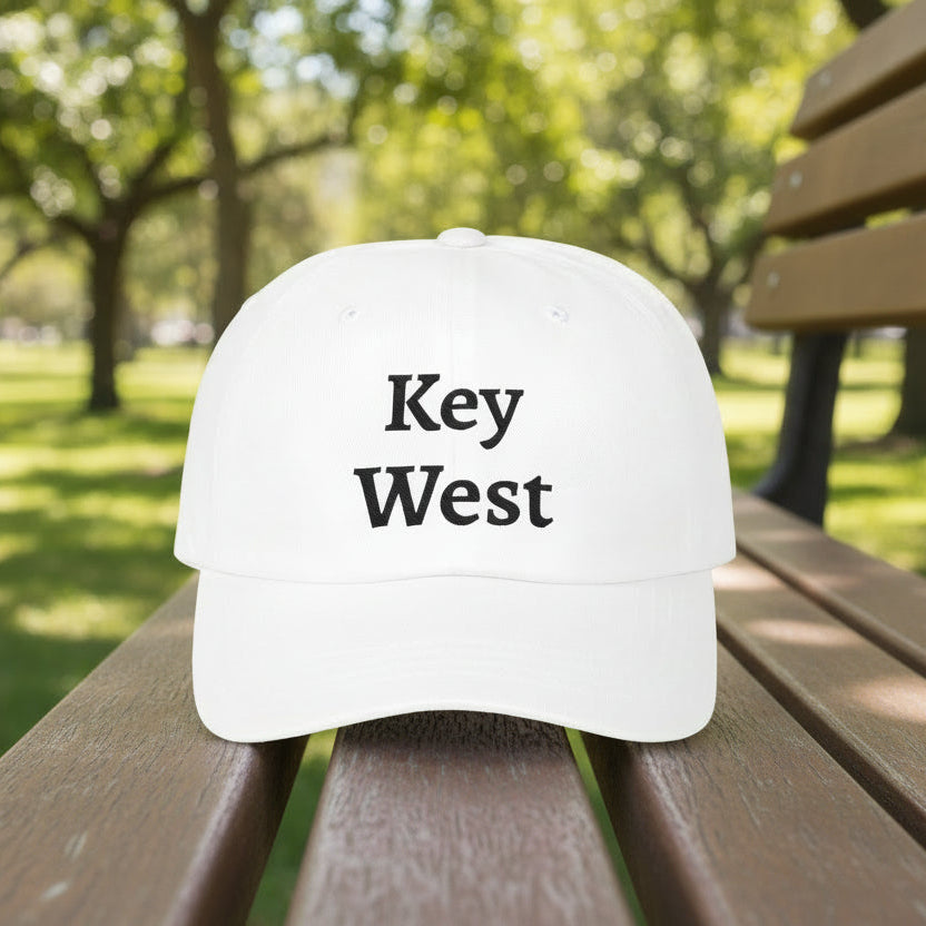 White cap with 'Key West' text on a wooden bench in a park.