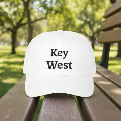 White cap with 'Key West' text on a wooden bench in a park.