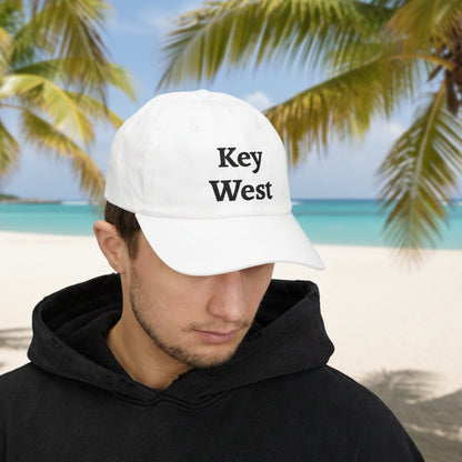 Person wearing a 'Key West' cap on a beach with palm trees in the background