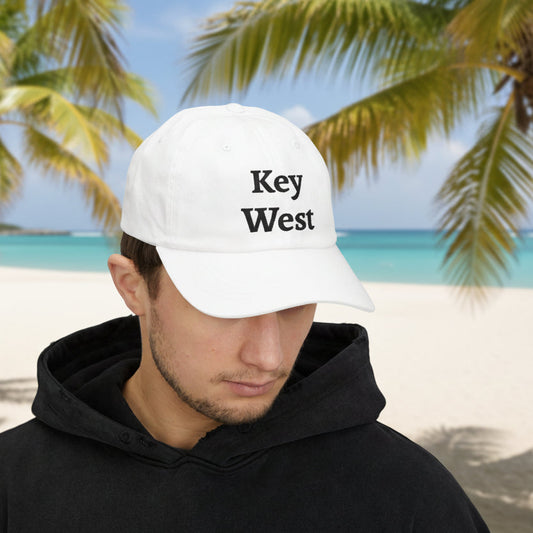 Person wearing a 'Key West' cap on a beach with palm trees in the background
