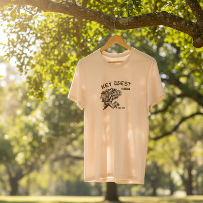 Pink t-shirt with a graphic design hanging on a tree branch in a park.