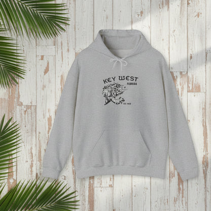 Gray hoodie with 'Key West, Florida' print on a wooden surface with palm leaves.