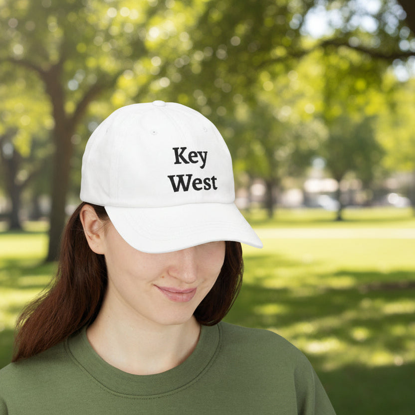 Person wearing a white cap with 'Key West' text in a park setting