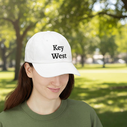 Person wearing a white cap with 'Key West' text in a park setting